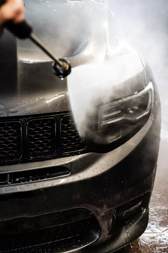 A black car being washed by a hose